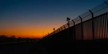 Modern border fence at dawn, symbolizing new security measures and their impact.